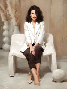 Портрет женщины с русыми, волнистыми волосами с прорисовкой Под масло, на женщине в белом пиджаке и коричневых брюках, женщина сидит в белом кресле, художник Виктория 