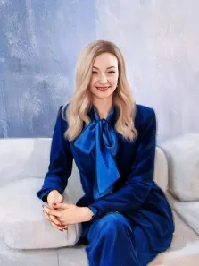 Женский портрет нарисованный в стиле Под масло, девушка в синем костюме сидит на белом диване, художник Виктория Б