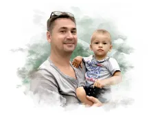 Семейный портрет под акварель.На портрете изображён улыбающийся мужчина в серой футболке с очками, сидящими на голове, который держит на руках маленького ребёнка. Ребёнок одет в серую футболку с ярким принтом и тёмные шорты, смотрит прямо перед собой с серьёзным выражением лица; фон выполнен в мягких акварельных тонах зелёного и белого, создающих лёгкую и уютную атмосферу. Художник: Евгения 