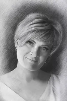 Женский портрет в стиле карандаш. На портрете изображена женщина с короткой светлой причёской, аккуратно уложенной; она слегка улыбается, её взгляд мягкий и доброжелательный. Рисунок выполнен в технике карандашного штрихования, с тщательной проработкой светотени на лице и волосах, фон плавно размыт, что подчёркивает выразительность образа. Художник: Татьяна 