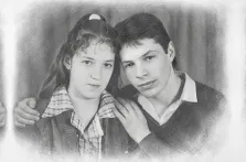 Парный портрет под карандаш. На портрете изображены молодой мужчина и девушка: мужчина в тёмном свитере поверх рубашки нежно обнимает девушку за плечи, а она, с волосами, собранными заколкой, одета в клетчатую рубашку и тёмную куртку. Их лица спокойны и серьёзны, взгляды устремлены прямо на зрителя, а мягкий размытый фон подчёркивает интимность момента. Художник: Татьяна 