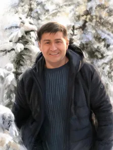 Мужской портрет под масло. На портрете изображён улыбающийся мужчина с короткими тёмными волосами, одетый в тёмную куртку поверх полосатого свитера; он стоит на фоне заснеженных елей, его поза расслаблена, а выражение лица передаёт доброжелательность. Художественная обработка изображения придаёт сцене лёгкую мазковую текстуру, создавая ощущение зимней живописи. Художник: Александра 