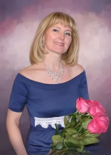 Женский портрет под масло. На портрете изображена женщина с аккуратной светлой причёской, в элегантном тёмно-синем платье с открытыми плечами и кружевной вставкой; она держит букет ярко-розовых роз и улыбается, излучая доброжелательность. Образ дополняют изысканные украшения — серьги и длинное колье с подвесками, а фон выполнен в мягких розово-фиолетовых тонах, создающих тёплую атмосферу. Художник: Антонина