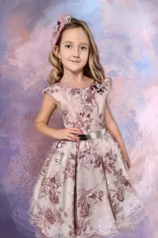 Детский портрет под масло. На портрете изображена девочка с длинными светлыми волосами, в нарядном платье с цветочным узором в пастельных тонах, подчёркнутом серебристым поясом; на голове — изящный розовый ободок с декоративными элементами. Фон выполнен в мягких акварельных оттенках сиреневого и розового, создающих лёгкую и романтичную атмосферу снимка. Художник: Александра 