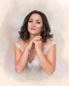 Женский портрет под масло. На портрете изображена женщина с тёмными волнистыми волосами, в лёгком белом платье с кружевными деталями; её руки сложены у подбородка, а на лице — мягкая, задумчивая улыбка. Фон выполнен в нежных пастельных тонах с лёгкими блестящими акцентами, создающими атмосферу лёгкости и утончённости. Художник: Анна