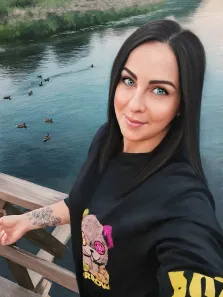 Женский портрет под масло. На картине изображена молодая женщина с длинными черными волосами и яркими голубыми глазами, стоящая на мосту у реки. На заднем плане видны утки, плавающие в воде, что создает спокойную и умиротворяющую атмосферу. Художник Софья