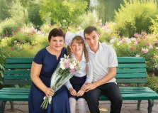 Семейный портрет под масло. На картине изображена семья из трёх человек — женщина, девочка и мужчина — сидящая на зелёной парковой скамейке. Девочка в школьной форме с бантами держит букет цветов, а взрослые расположились по бокам от неё; на фоне — цветущий сад с обилием розовых и белых цветов и зелёной листвы. Художник Ирина
