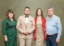 Семейный портрет под масло. Четыре человека стоят рядом на фоне приглушённого зелёного полотна. Слева направо — женщина в зелёном платье с поясом, молодой мужчина в светлом костюме с бабочкой, молодая женщина в бежевом платье с ярким красным шарфом и пожилой мужчина в голубой рубашке и джинсах. Художник Ирина