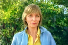 Женский портрет под масло. На картине изображена женщина с короткими светлыми волосами, в жёлтой рубашке и светло-голубой куртке. Она стоит на фоне густой зелёной листвы, её лицо спокойно и доброжелательно, взгляд направлен прямо на зрителя. Художник Анастасия 