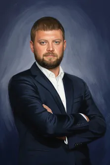 Мужской портрет в стиле под масло. На картине изображён мужчина с короткой стрижкой и бородой, одетый в тёмный пиджак и белую рубашку. Он стоит со скрещёнными на груди руками, смотрит прямо вперёд с серьёзным выражением лица, а фон выполнен в приглушённых синих тонах, подчёркивающих его фигуру. Художник Анастасия