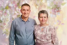 Парный портрет в стиле под масло. На картине изображён парный портрет: мужчина в светло-голубой рубашке стоит рядом с женщиной в нежно-розовой блузе с цветочным узором. Фон выполнен в акварельной технике с изображением лёгких, размытых цветов пастельных оттенков, создающих романтичную и тёплую атмосферу. Художник Анна
