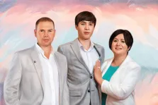 Семейный портрет в стиле под масло. На картине изображён семейный портрет: мужчина в светлом пиджаке и белой рубашке, молодой человек в сером костюме и женщина в белом пиджаке поверх бирюзового платья, стоящая с рукой у груди. Фон выполнен в мягких пастельных тонах с абстрактными мазками розового, голубого и белого цветов, создающими лёгкую и гармоничную атмосферу. Художник Александра