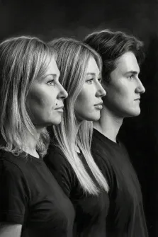 Семейный портрет в стиле под масло. На портрете в профиль изображены трое членов семьи: женщина слева, молодая женщина в центре и молодой мужчина справа. Все одеты в тёмные футболки, смотрят в одну сторону, их лица серьёзны и сосредоточенны; монохромная гамма и тёмный фон подчёркивают выразительность черт и создают ощущение семейного единства. Художник: Ирина