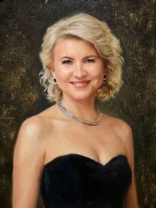 Женский портрет под масло. На портрете изображена женщина с короткими светлыми волнистыми волосами, одетая в элегантное чёрное платье без бретелек; она носит массивное серебряное колье и квадратные серьги, а на лице у неё — тёплая, доброжелательная улыбка. Тёмный фон с золотистыми бликами подчёркивает утончённость образа и придаёт картине торжественность. Художник: Ирина