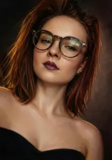 Женский портрет под масло. На портрете изображена молодая женщина с рыжими волосами средней длины, в крупных круглых очках и с выразительной тёмно-бордовой помадой; её взгляд слегка задумчив, а голова чуть наклонена вбок. Она одета в чёрное платье без бретелек, фон выполнен в приглушённых тёмных тонах, подчёркивающих её образ. Художник: Ирина