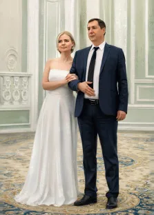 Парный портрет под масло. На портрете изображена свадебная пара: мужчина в строгом тёмно-синем костюме с белой рубашкой и чёрным галстуком стоит рядом с женщиной в элегантном белом платье без бретелек; они держатся за руки, их позы сдержанны и торжественны. Фон композиции — изысканный интерьер с пастельными стенами, декоративными элементами и узорчатым ковром, создающий атмосферу классического торжества. Художник: Александра 