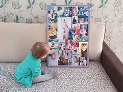 Ребенок, сидя на диване, рассматривает холст по фото на заказ с его собственными фотографиями.