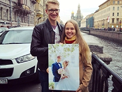 Пара с фотографией на холсте в руках на фоне вида с Невского проспекта на Спас на Крови в Петербурге.