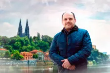 Мужской портрет Под масло, мужчина в синей осенней куртке стоит на фоне озера и исторических зданий, художник Артём