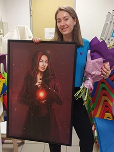 Девушка с подарками: цветами и портретом на холсте в рамке, на котором она изображена с огненным шаром