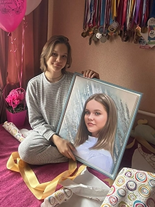 Девушка, сидя на кровати, развернула подарок - портрет по ее фотографии на холсте в рамке