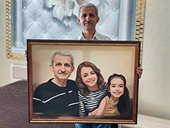 Мужчина с портретом на холсте своей семьи; на картине изображен он, его жена и дочь