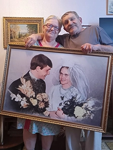 Пожилая пара держит подарок — портрет в багетной раме на холсте по их свадебной фотографии в молодости
