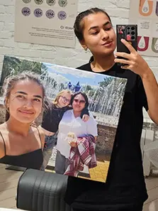 Девушка делает селфи с семейным фото, напечатанным на холсте