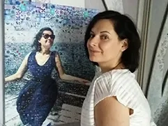 На фото изображена женщина, которая держит в руках фотомозаику на холсте, где ее портрет в темном платье составлен из маленьких фотографий